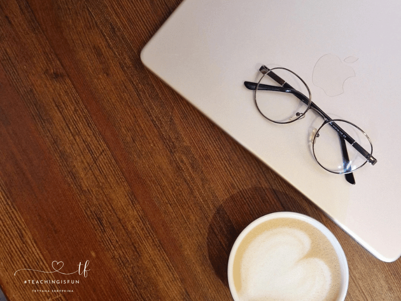 Laptop, glasses, and a cup of coffee on a wooden table in a cafe.